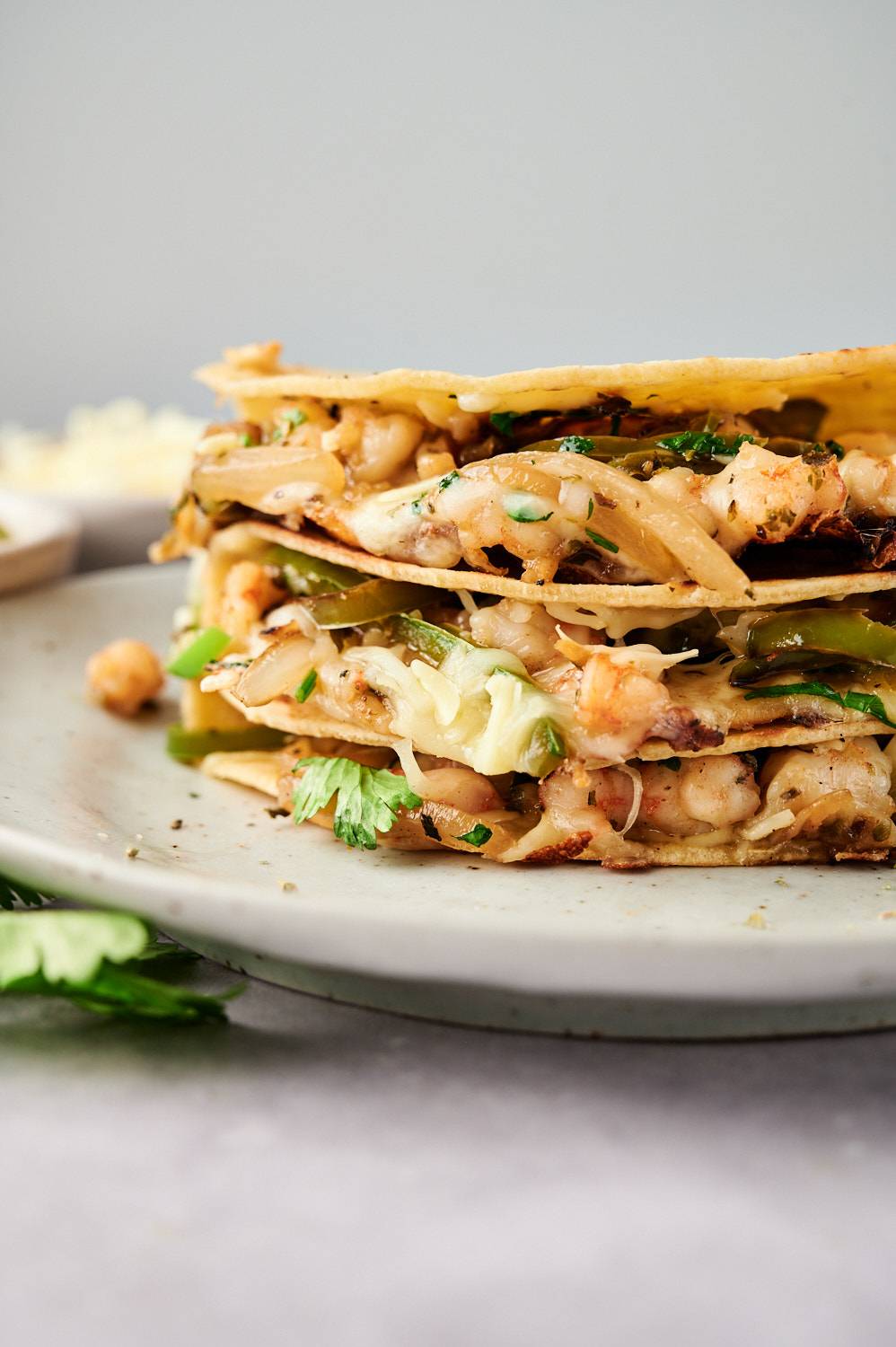 Shrimp tacos gobernador piled on a plate with melted cheese, onions, peppers, and cilantro.