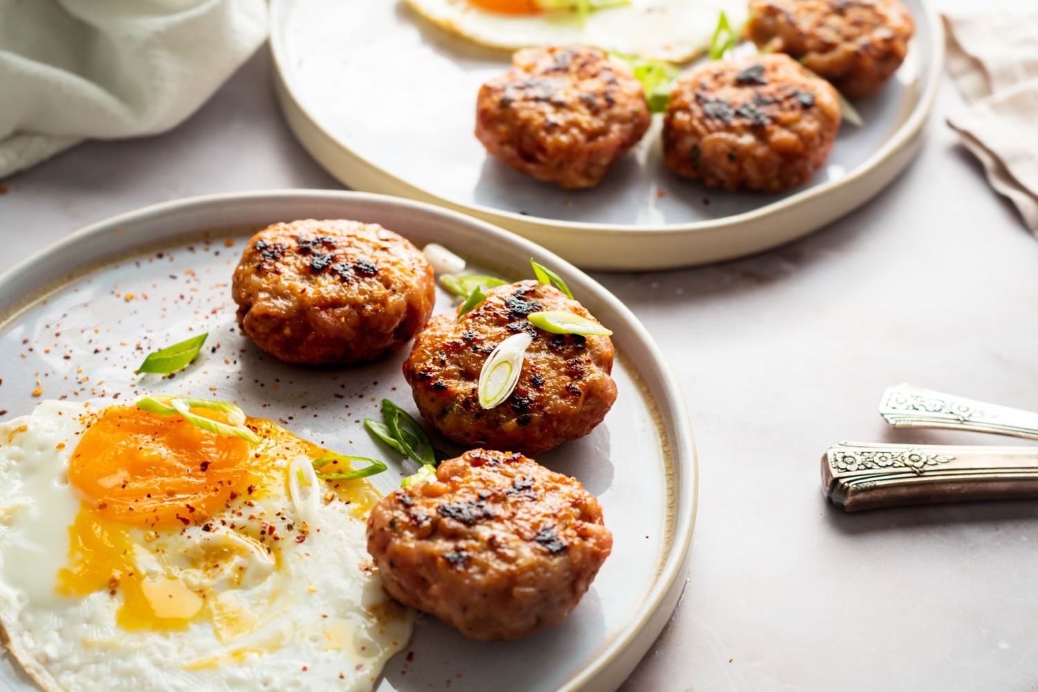 Turkey sausage patties for breakfast served with eggs on a white plate.