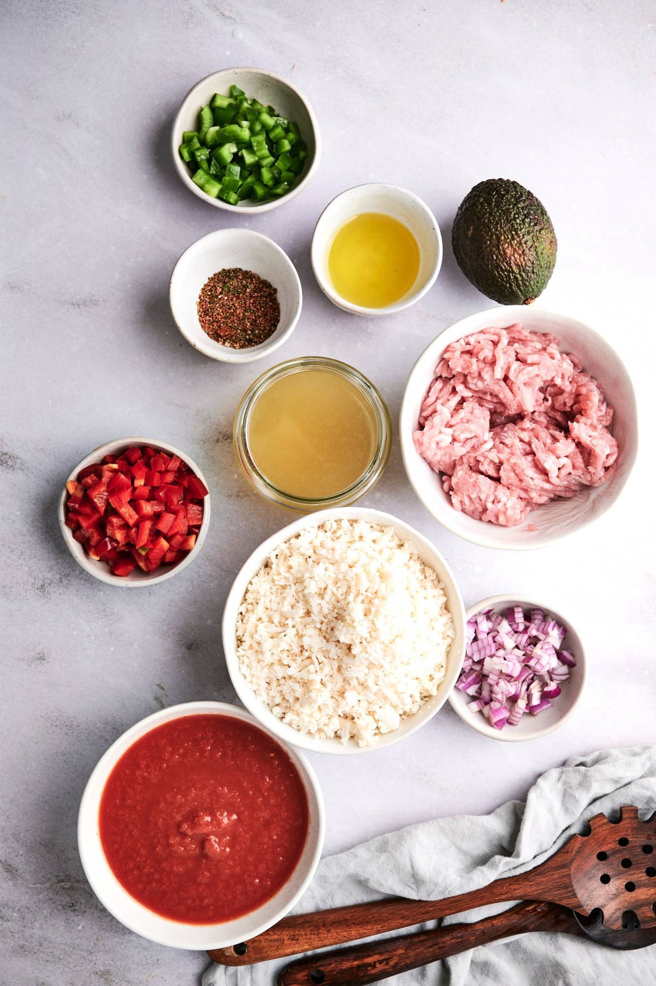 Ingredients for taco turkey and cauliflower rice skillet including ground turkey, salsa, onions, pepper, taco seasoning, avocado, and cauliflower rice.