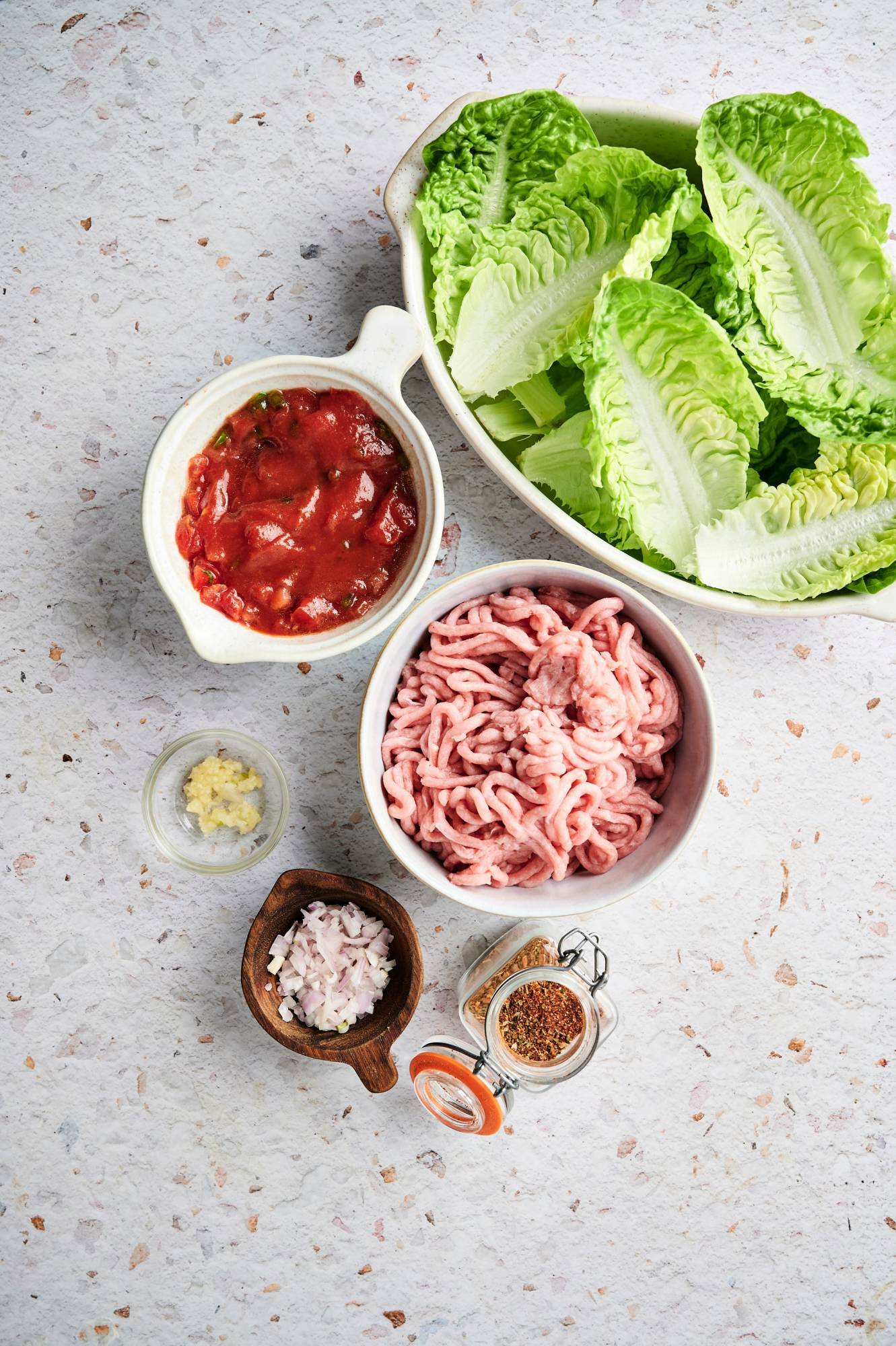Ingredients for turkey taco lettuce wraps including ground turkey, onion, garlic, taco seasoning, lettuce leaves, and diced tomatoes.