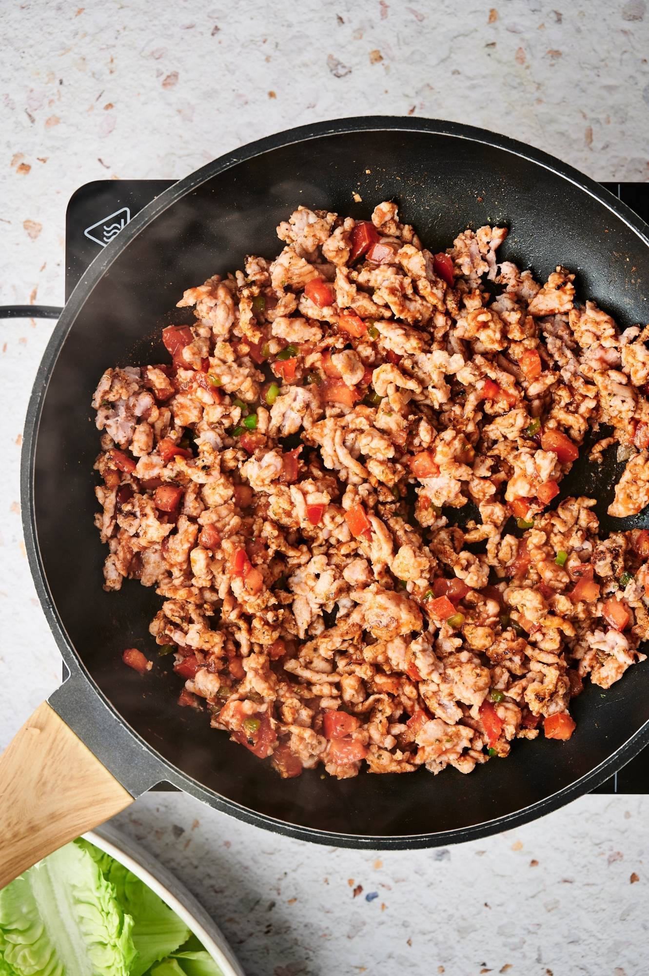 Ground turkey taco meat with tomatoes, onions, and taco seasoning in a skillet.