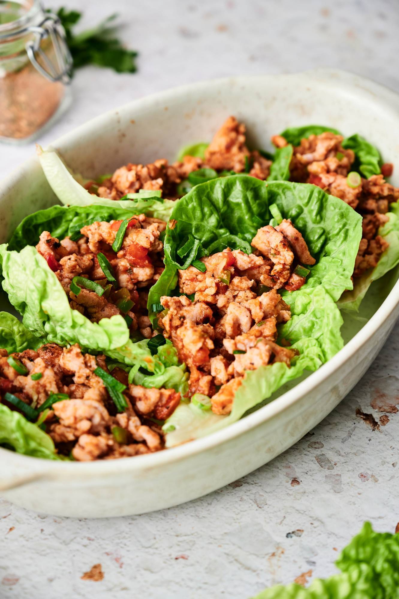 Taco lettuce wraps with ground turkey, tomatoes, cilantro, and green onions served in butter lettuce leaves.