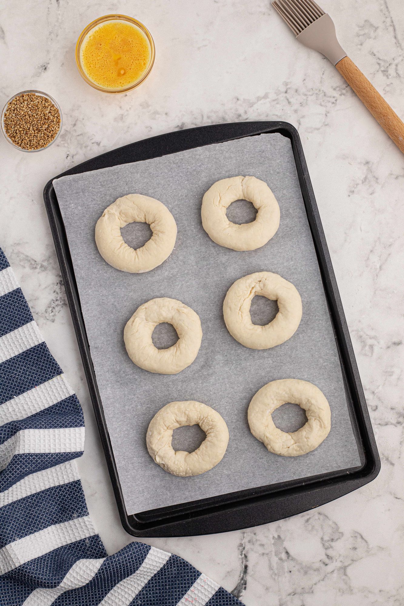 Two ingredient dough rolled into bagels on a baking sheet with parchment paper.