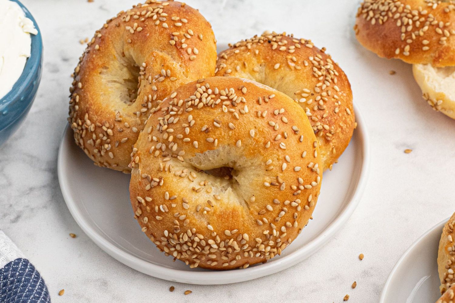 Sesame seed two ingredient dough bagels cooked until golden brown on a plate with cream cheese.