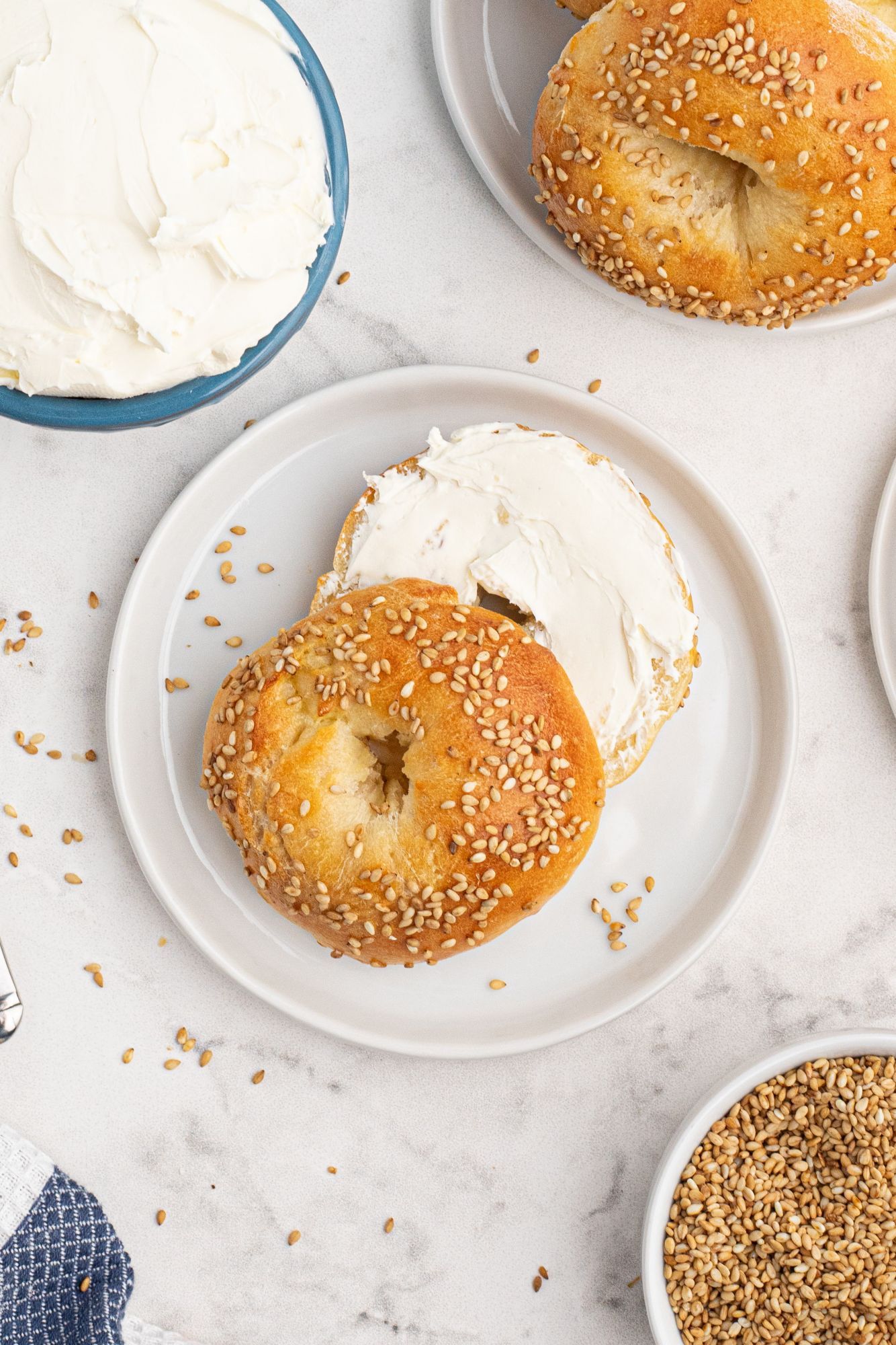 Greek yogurt bagel with sesame seeds sliced in half and covered with cream cheese.