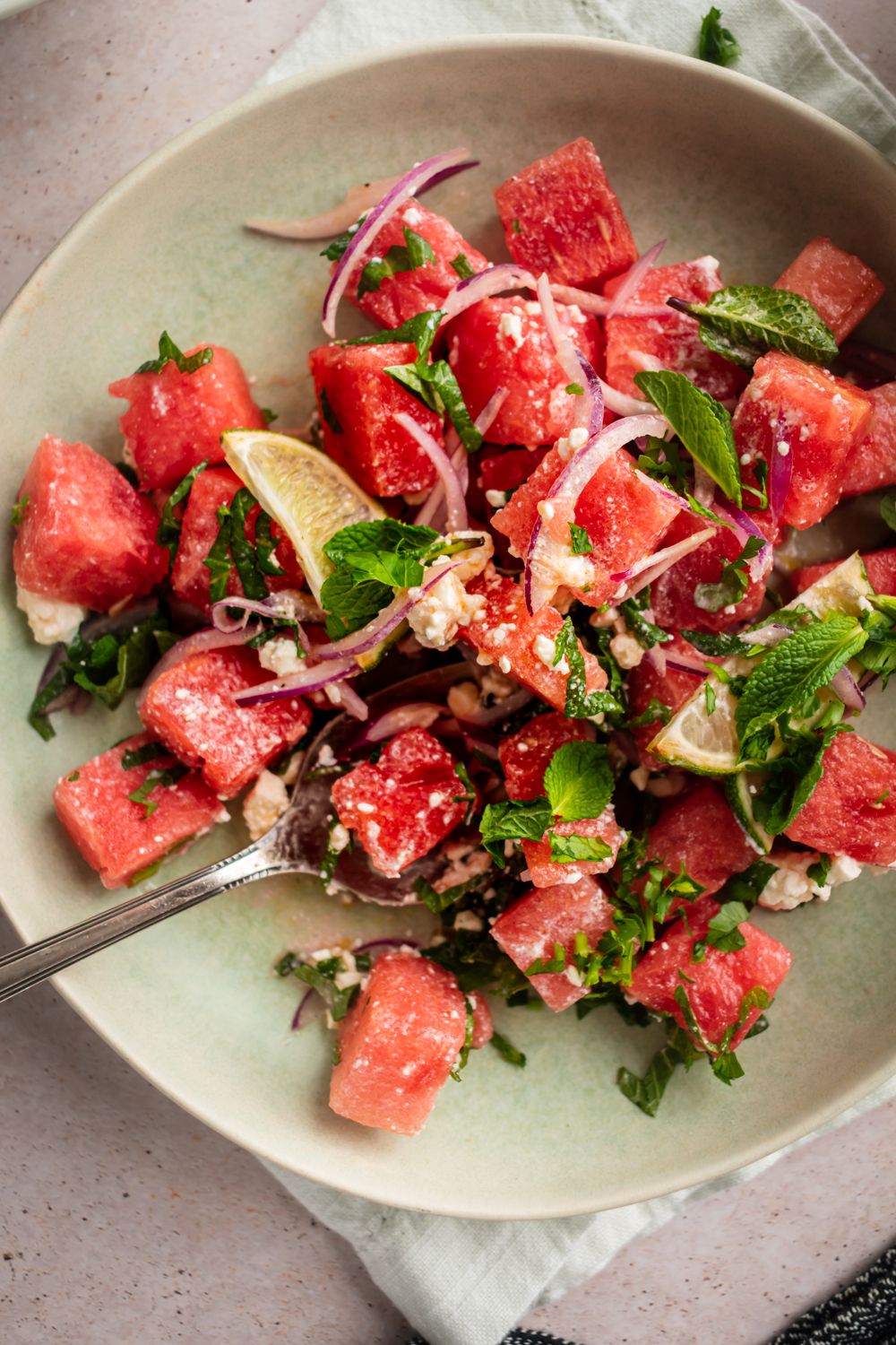 Fresh watermelon salad with mint and feta cheese served with red onions and lime.