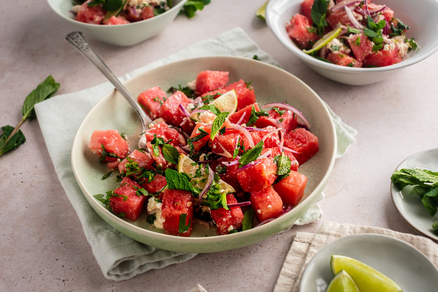 Summer watermelon and mint salad with crumbled feta cheese and red onion in two bowls.