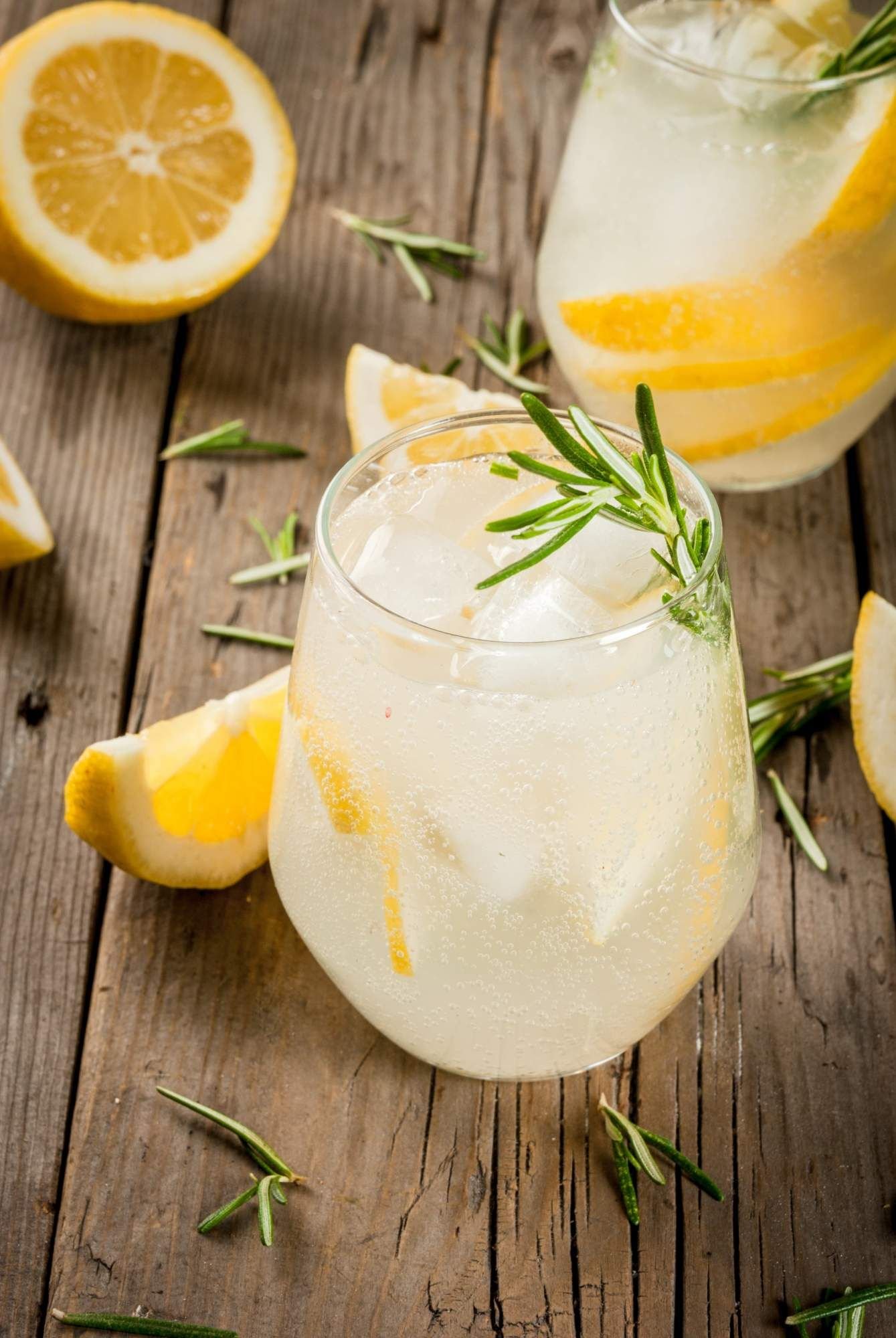 Spritzer with white wine and soda water served with lemon slices and fresh rosemary. 