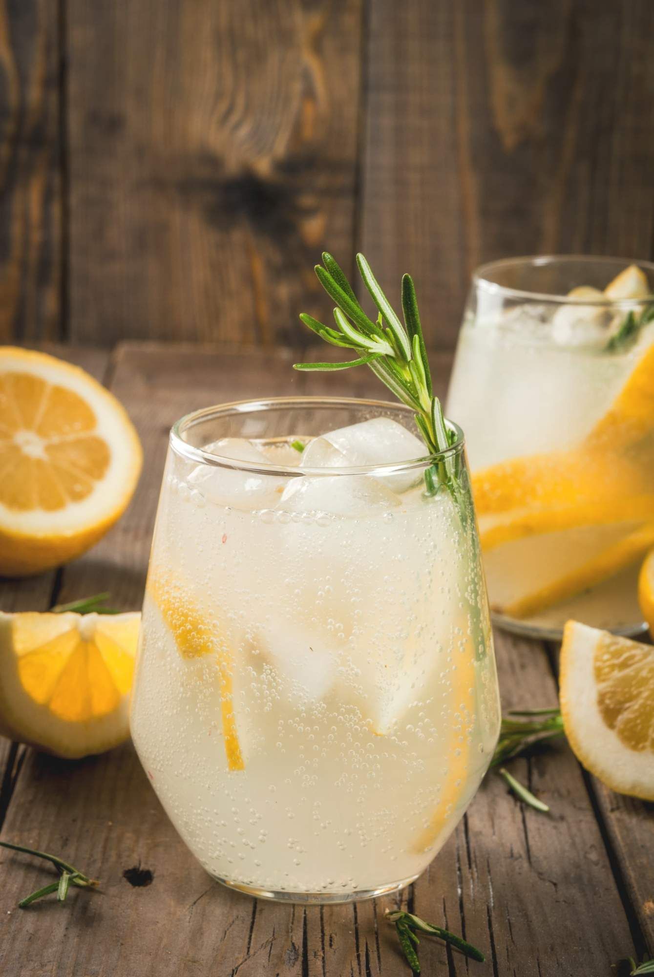 Wine spritzer with white wine and seltzer in a glass with lemon and rosemary. 