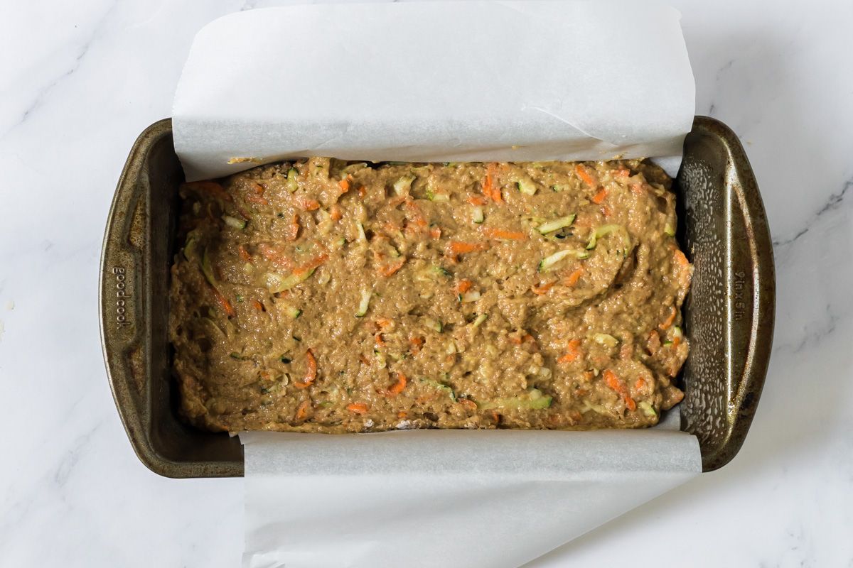 Carrot and zucchini bread batter in a pan with parchment paper.