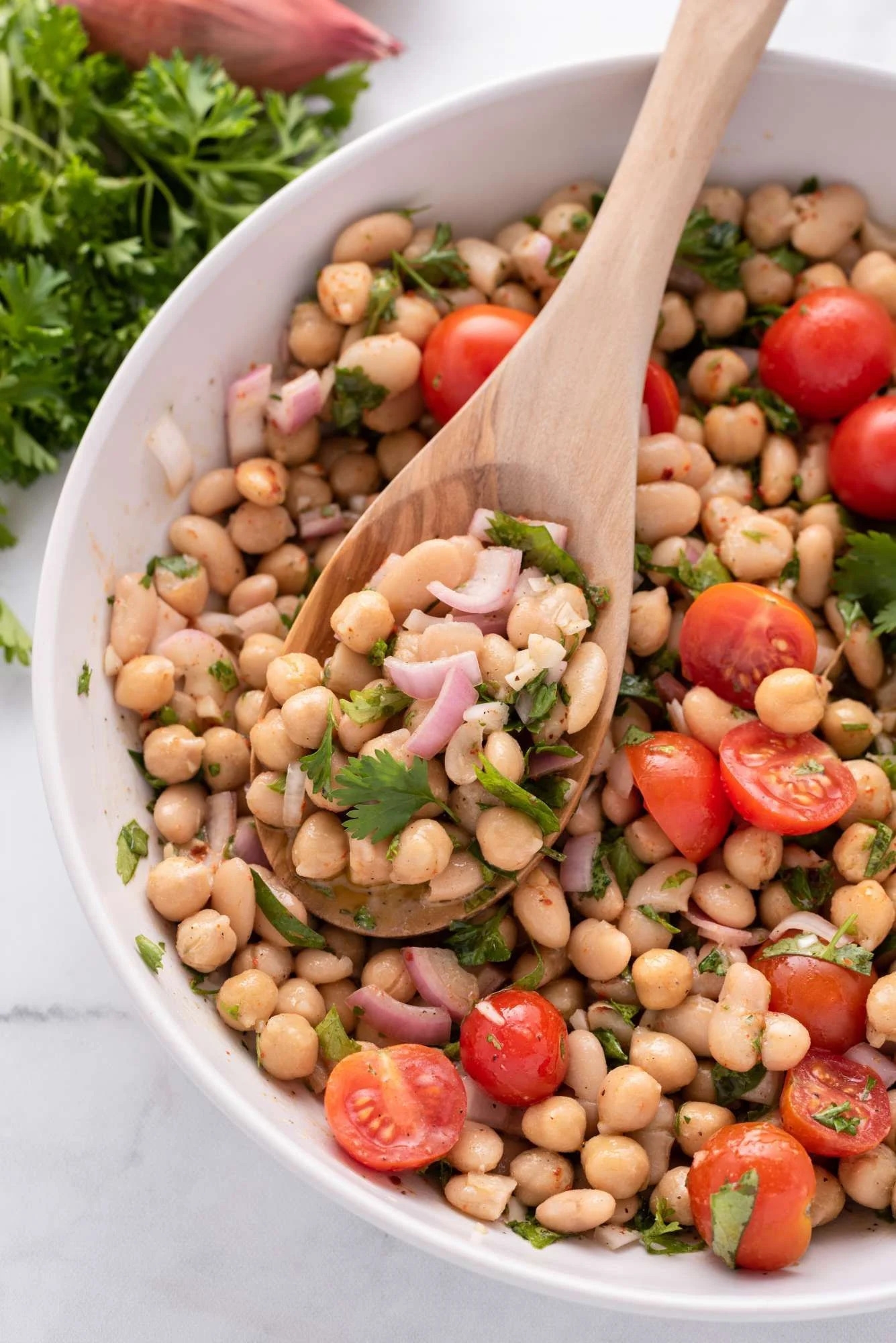 Marinated bean salad with chickpeas, white beans, herbs, tomatoes, and shallots.