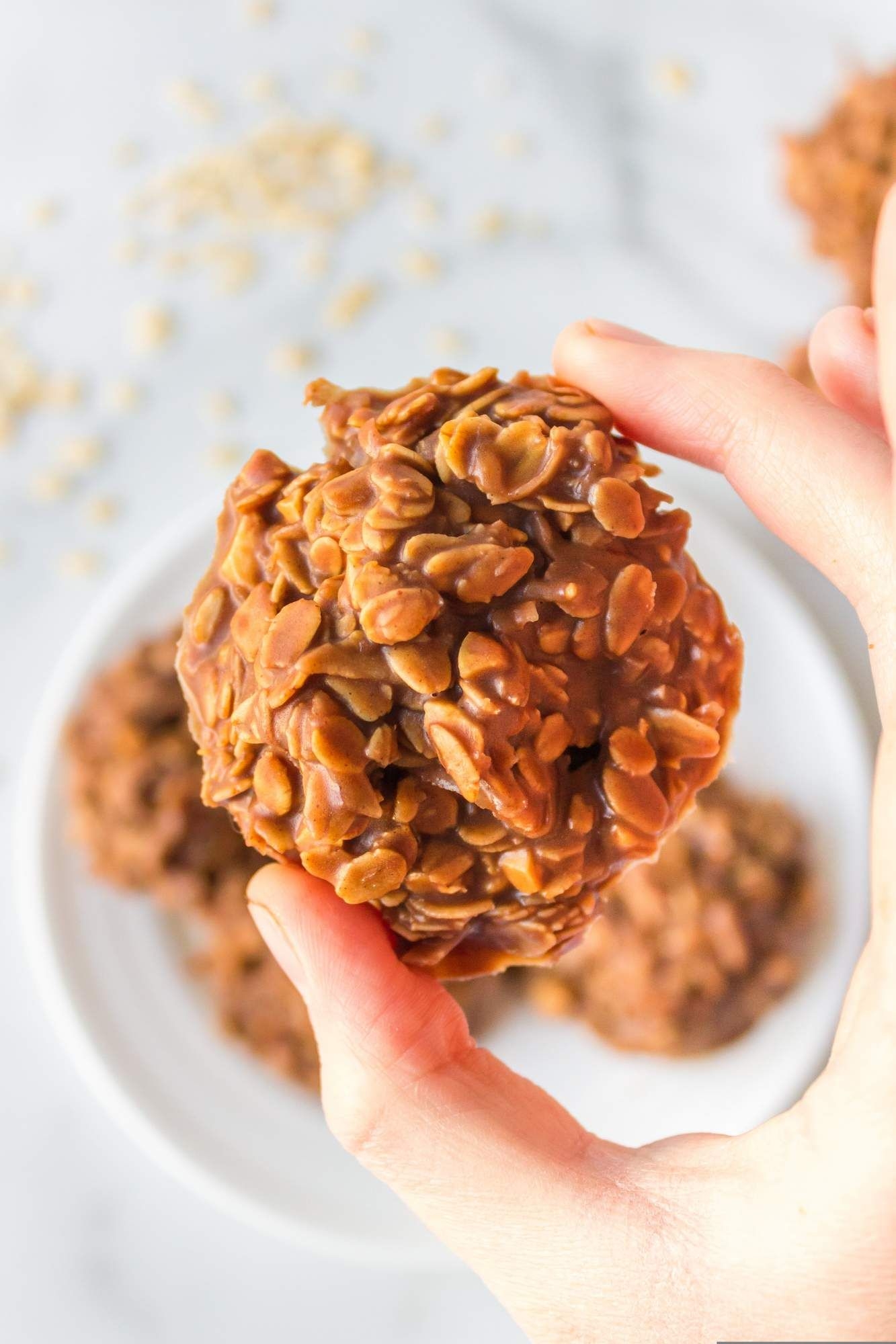 No bake oatmeal cookies with chocolate and peanut butter being held up by a hand.