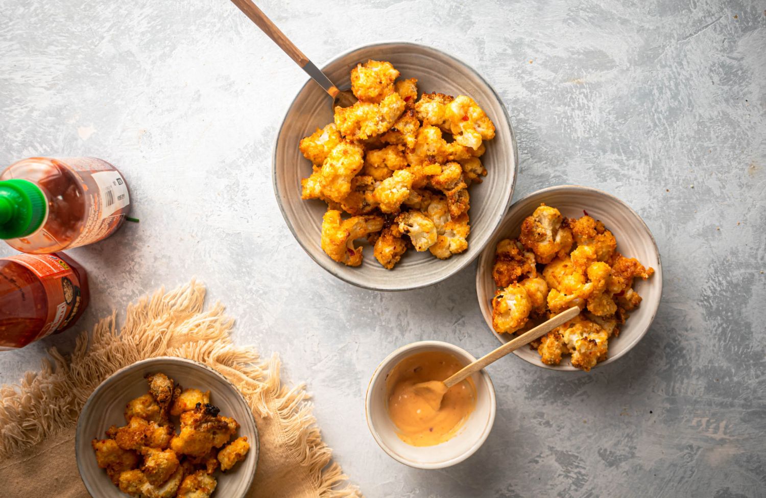 Bang bang cauliflower in two bowls served with a sweet and spicy sauce.