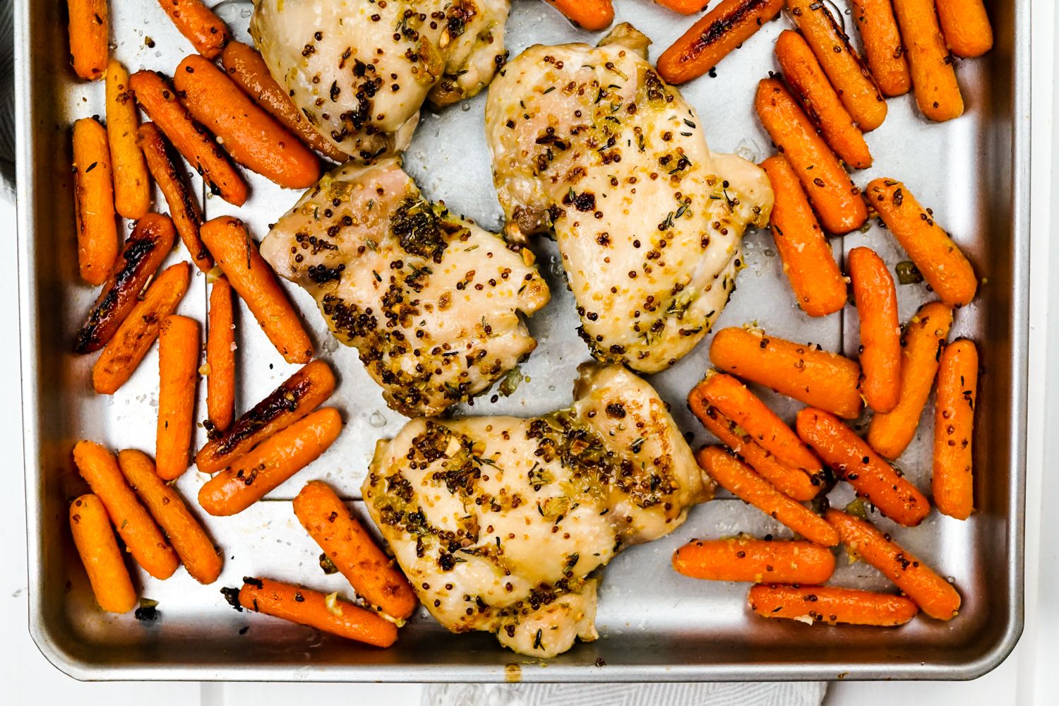 Honey mustard chicken and carrots cooked on a single sheet pan.