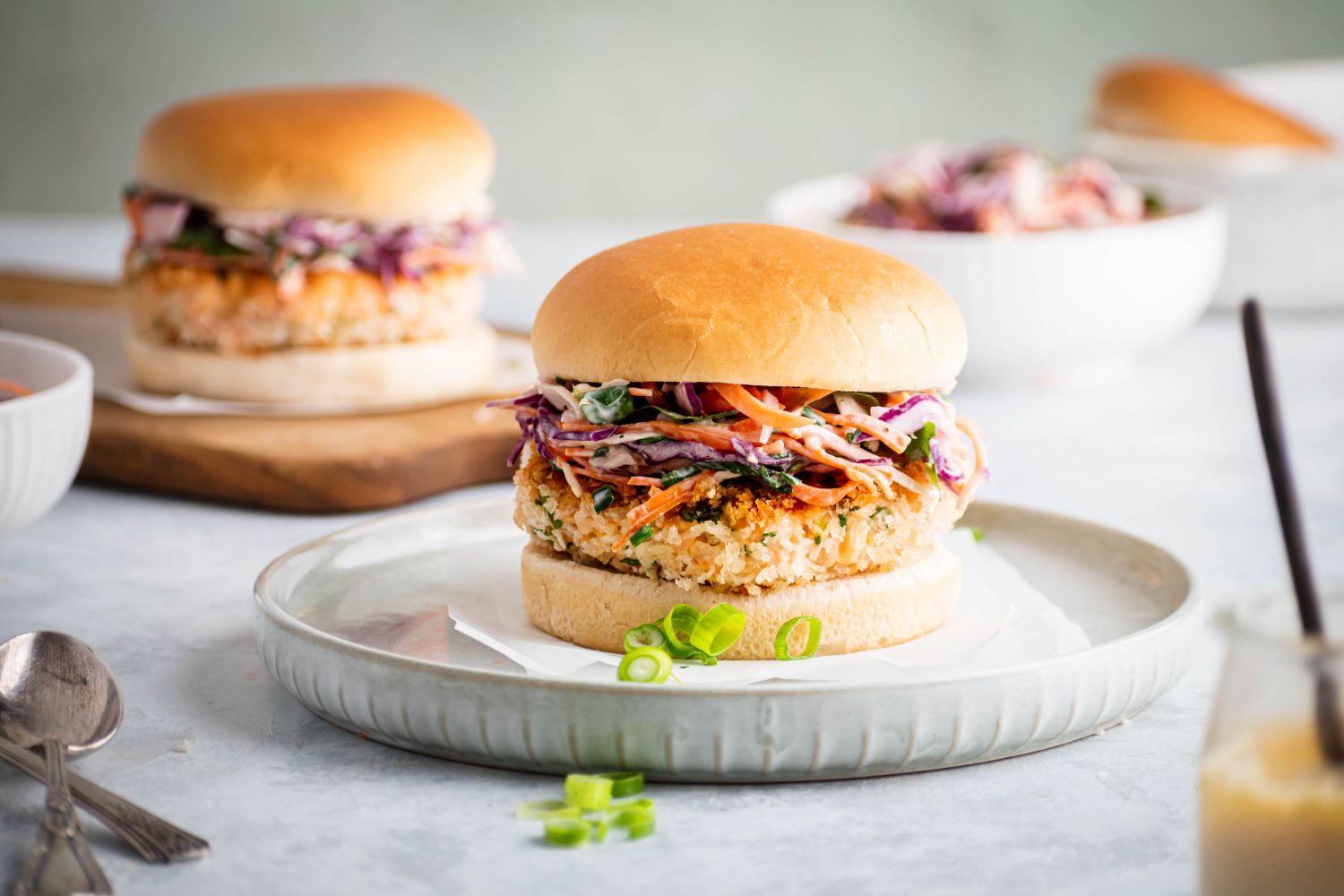 Salmon burgers with coleslaw on top served on a whole grain roll.