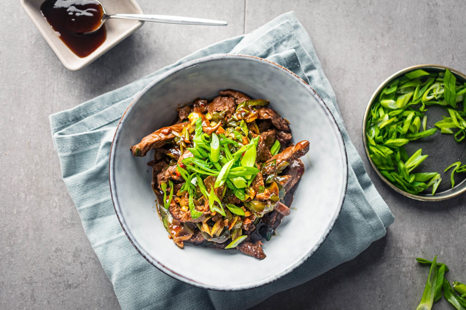 Mongolian beef in a bowl with sliced green onions.