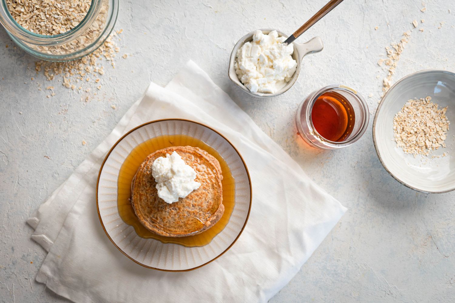 Oatmeal protein pancakes with maple syrup and whipped cream on a plate.