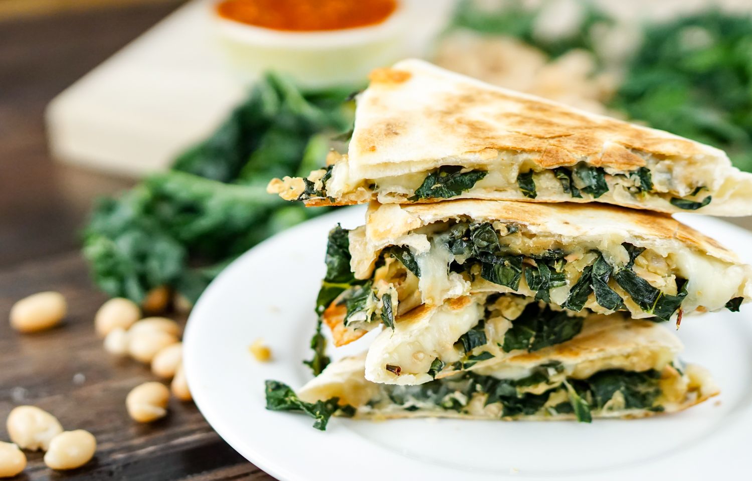 Kale and white bean quesadillas stacked in a pile with kale on the side.