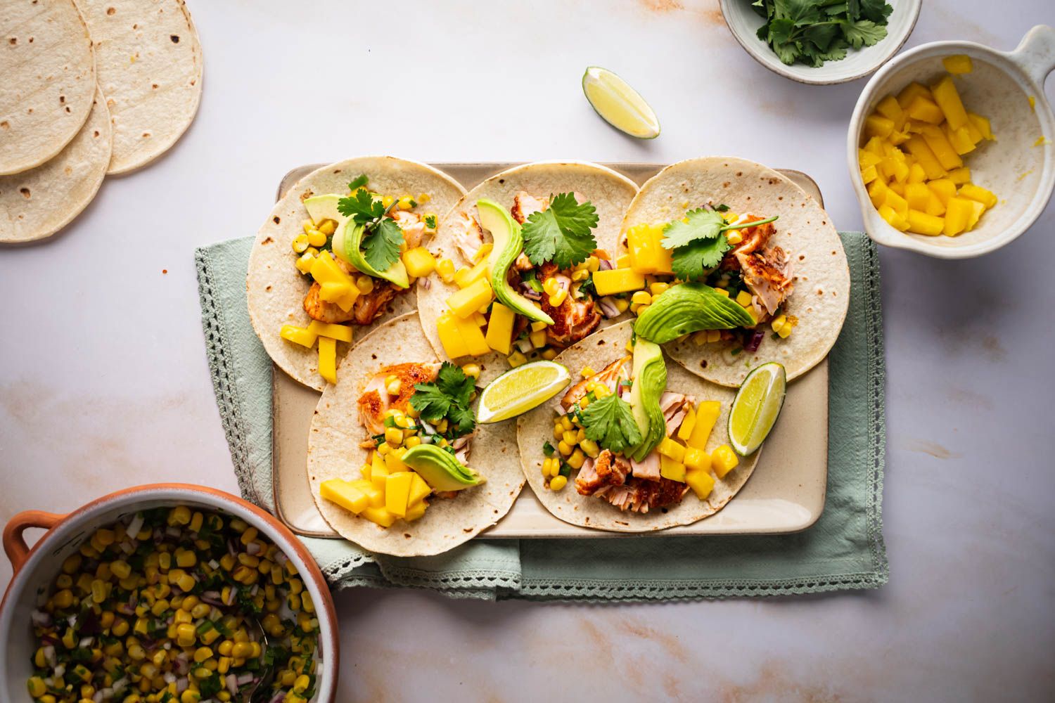 Salmon tacos with corn salsa, avocado, cilantro, and red onion served on corn tortillas. 