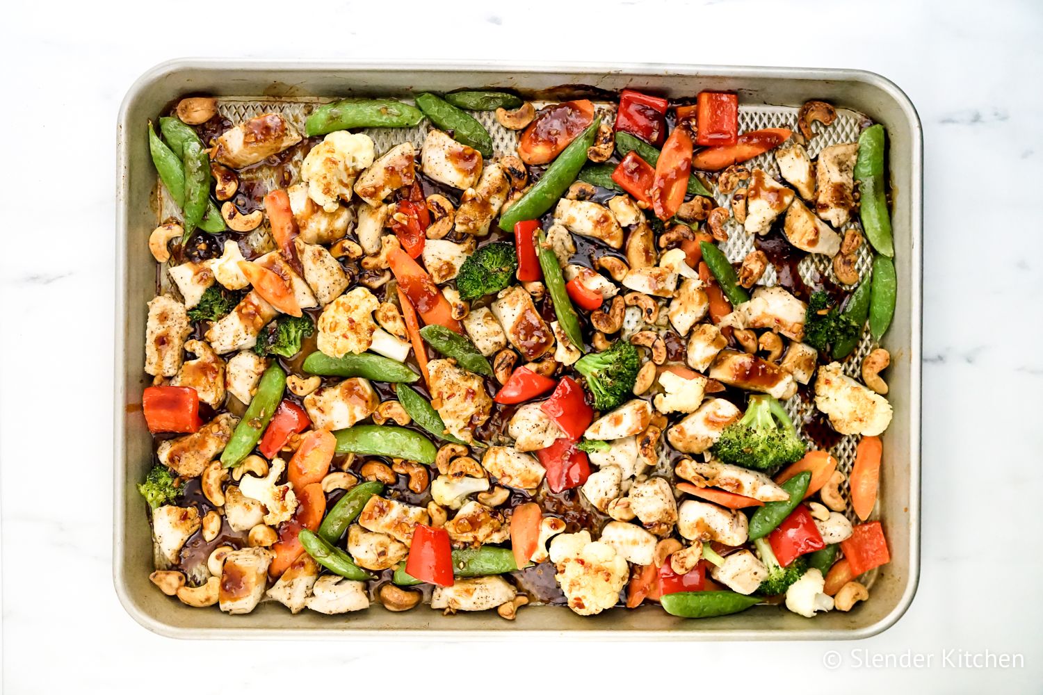 Sheet Pan Cashew Chicken with vegetables and sauce drizzled on top.