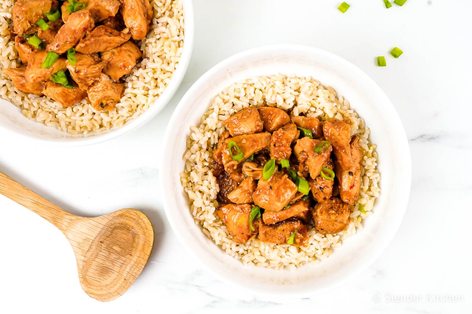 Slow Cooker Honey Garlic Chicken on a plate with brown rice and green onions.