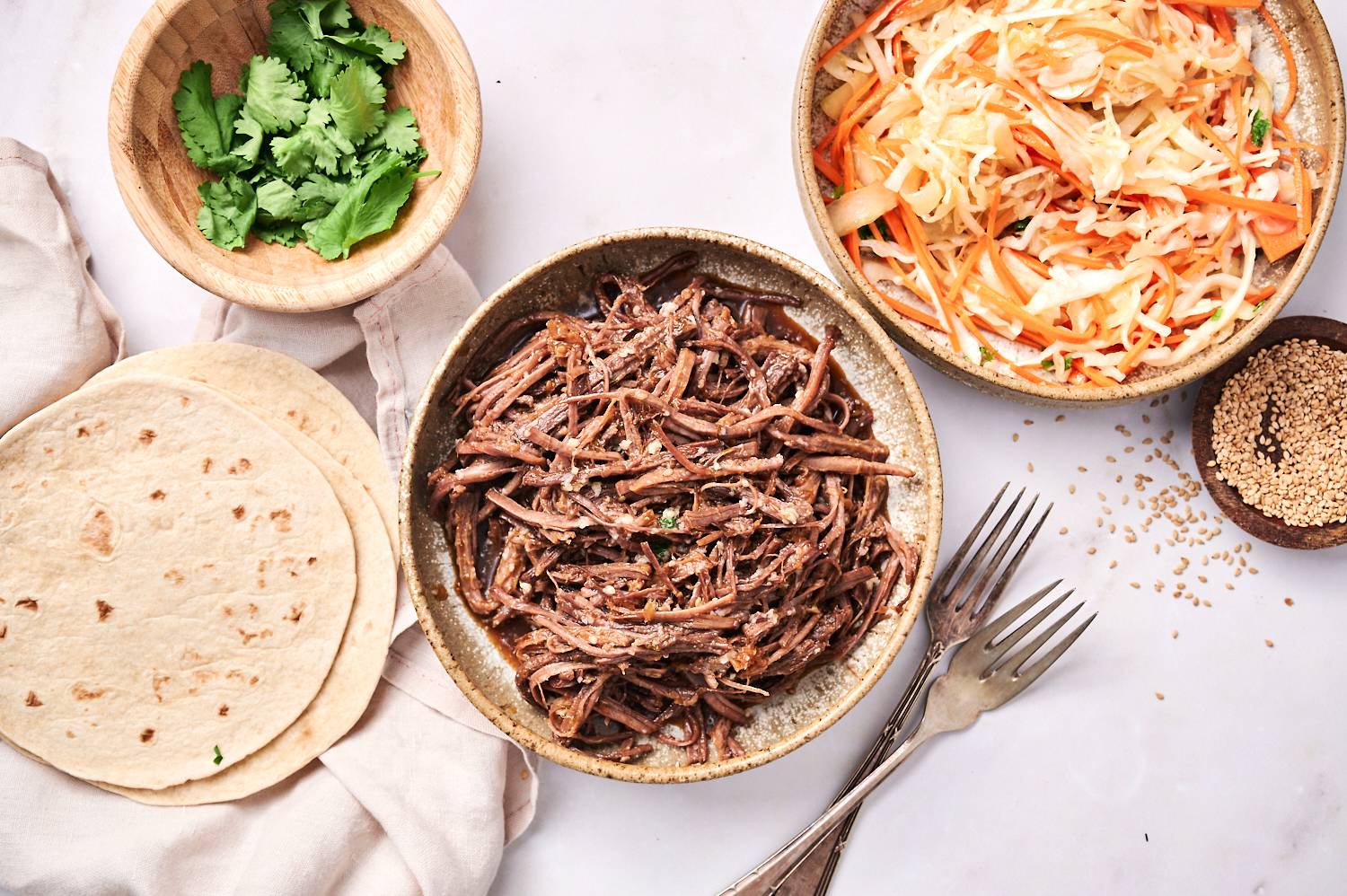 Crockpot Korean Beef Tacos with Asian slaw in corn tortillas with cilantro.