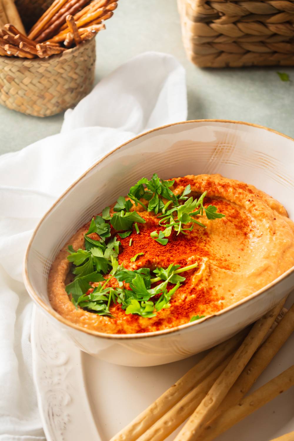 Roasted red pepper hummus in a bowl with fresh parsley and smoked paprika. 