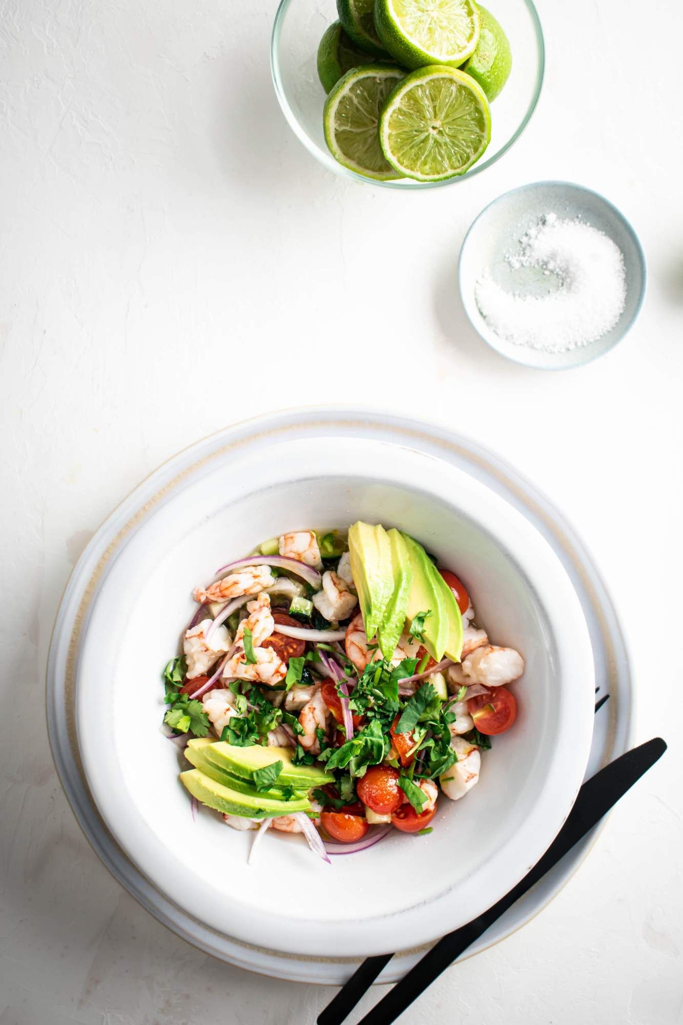 Ceviche with shrimp, avocado, cilantro, tomato, cucumber, and lime juice in a bowl.
