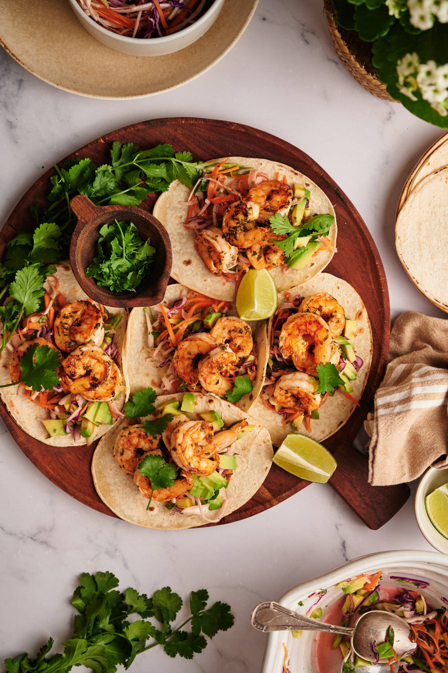 Shrimp and slaw tacos with cabbage, seasoned shrimp, avocado, and cilantro served on warm tortillas.