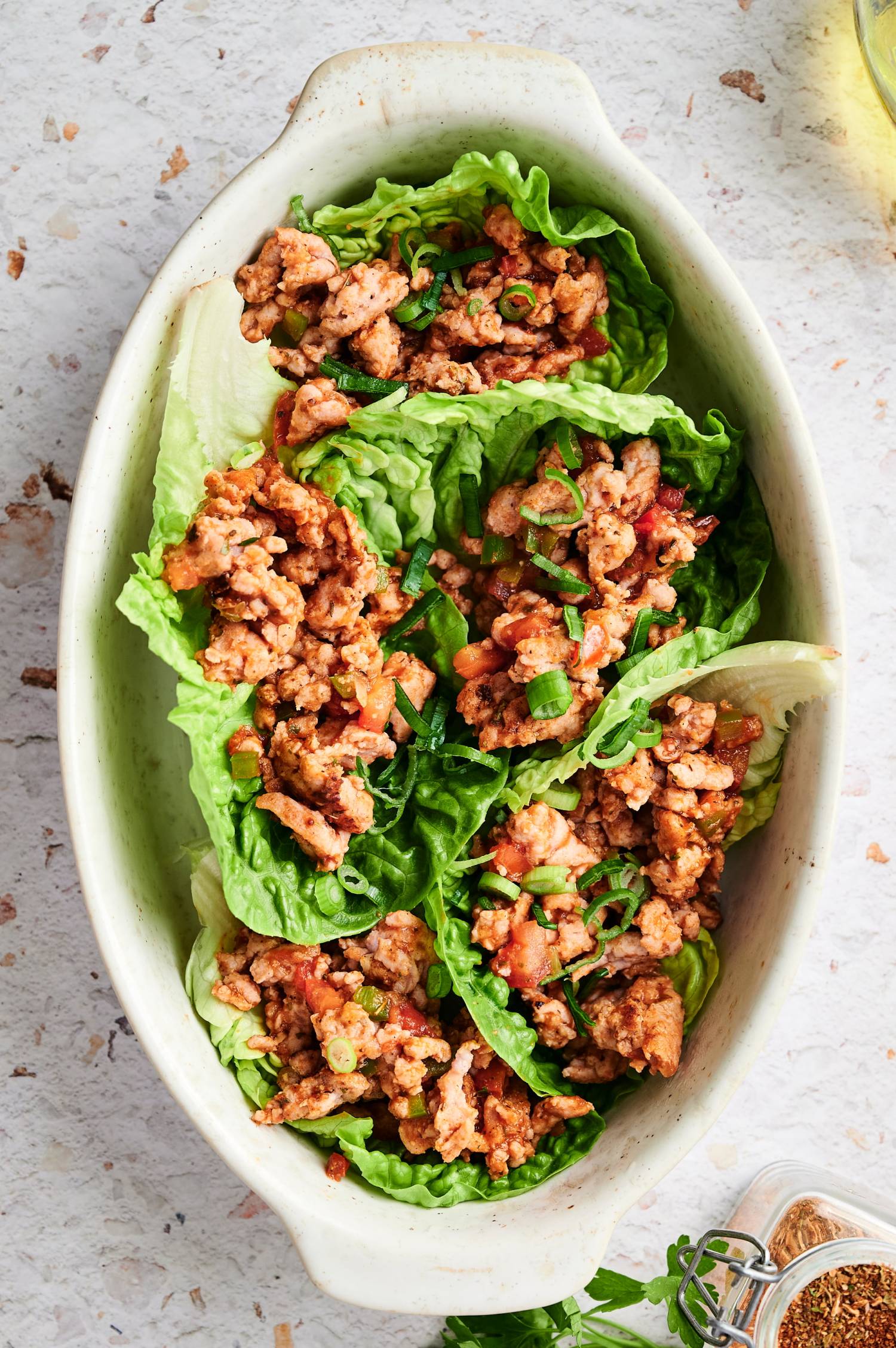 Ground turkey taco lettuce wraps in Romaine lettuce served in a white dish.