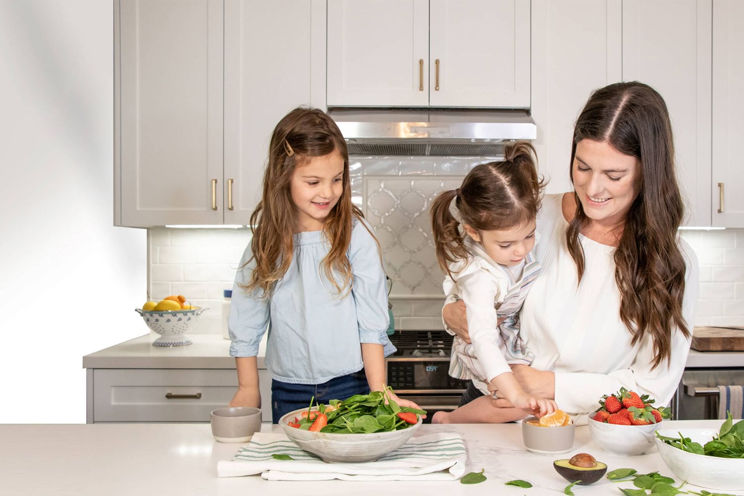 Mom cooking with two kids in the kitchen.