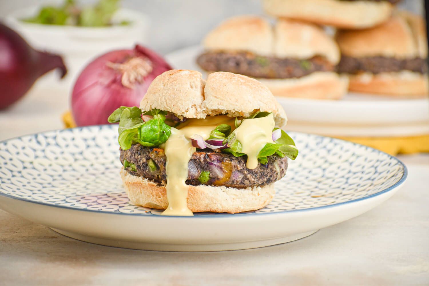 Jalapeno cheddar black bean burgers on a bun with lettuce, tomato, and onions.