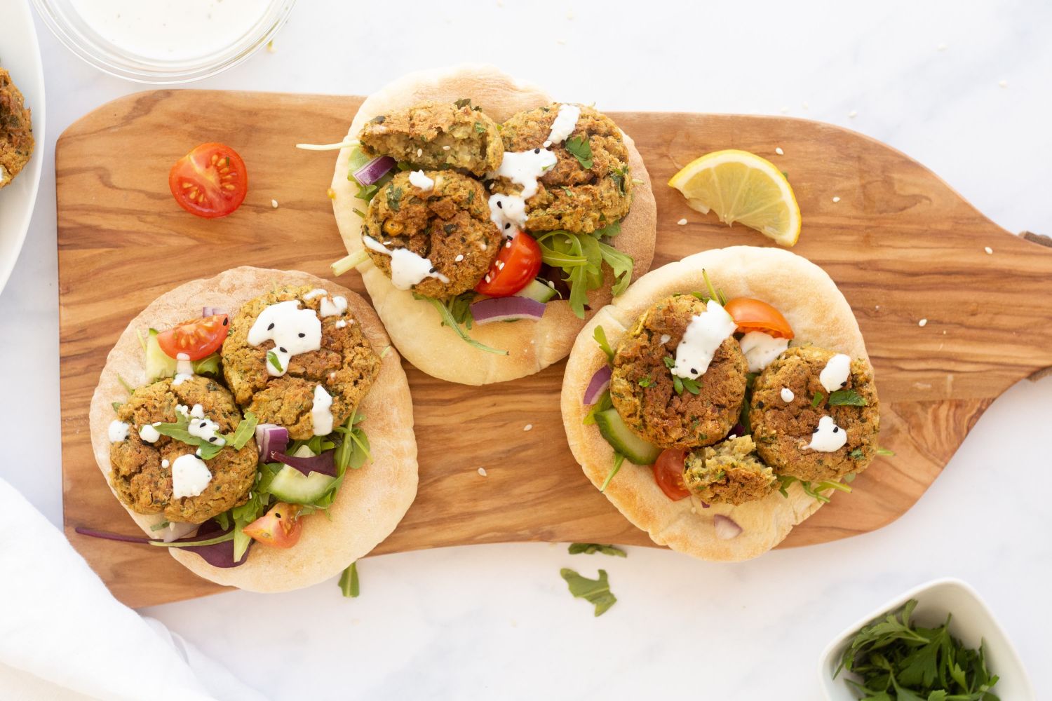 Baked falafel made with chickpeas and fresh herbs served with fresh vegetables, pita bread, and tahini.