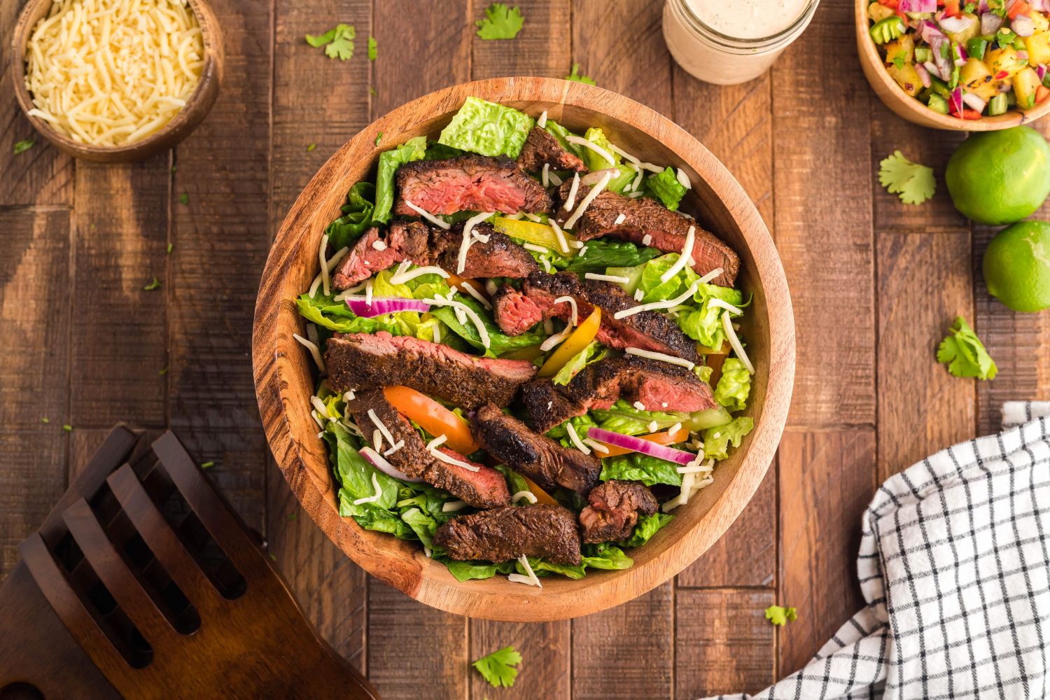 Blackened steak salad with thinly slcied steak over a bed of Romaine lettuce, red onion, peppers, and cheese.