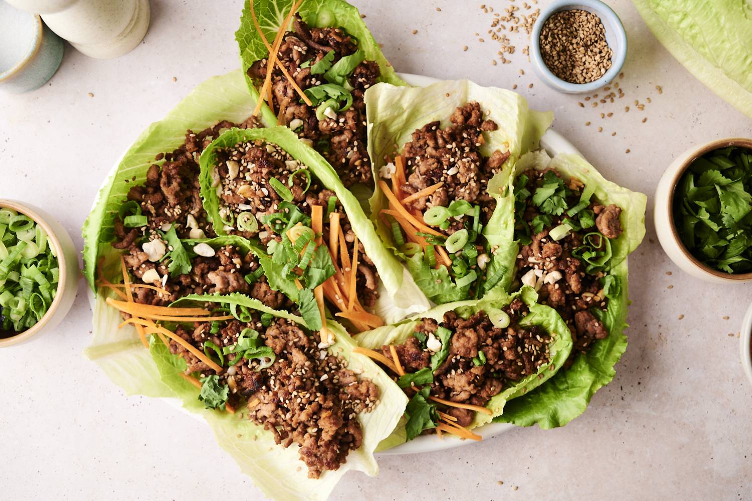 A top-down shot of a plate of Korean beef lettuce wraps and a side of shredded carrots.
