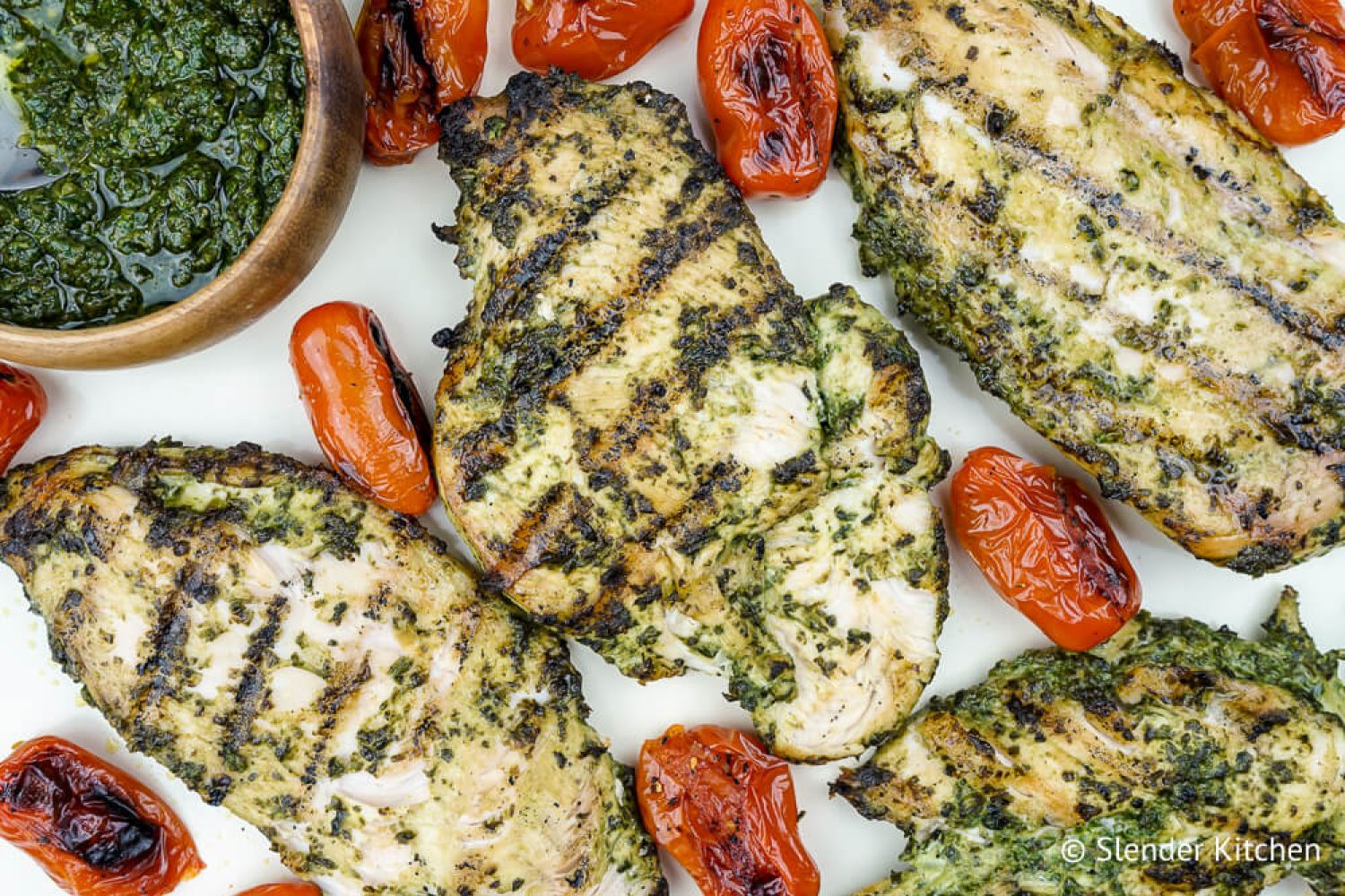 Pesto chicken cooked on the grill with cherry tomatoes and extra pesto sauce.