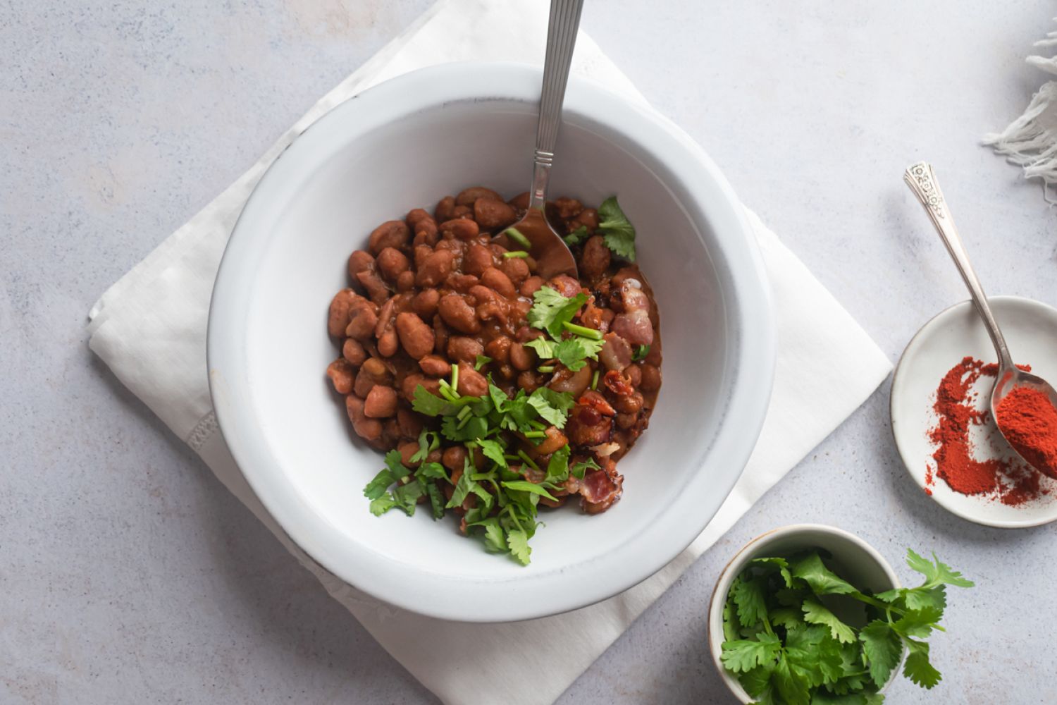 Slow cooker borracho beans in a bowl with cilantro, crispy bacon, and beer broth.