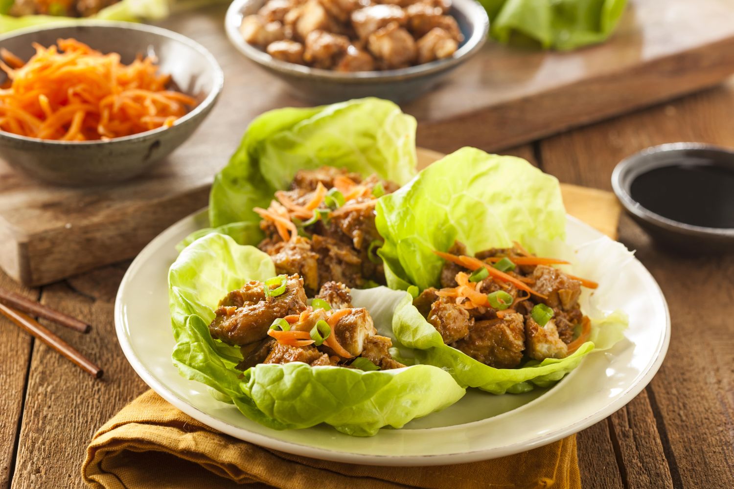Slow Cooker Korean Chicken in lettuce wraps with shredded carrots on top.