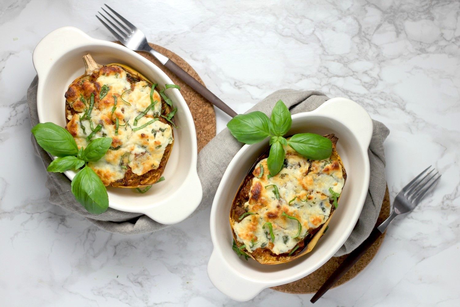Spaghetti squash lasagna boats in two casserole dishes with basil.
