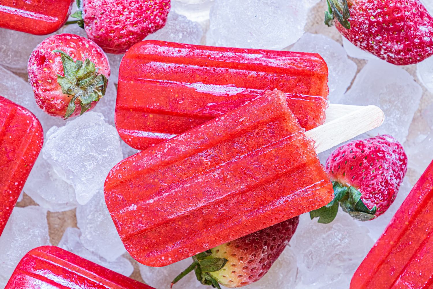 Strawberry popsicles made with fresh strawberries and honey served on a plate with ice.