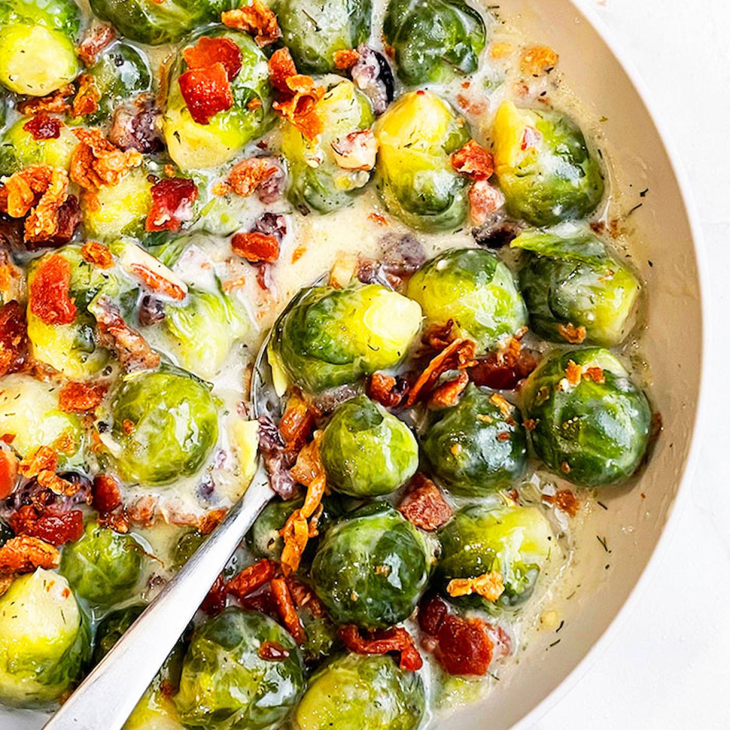Slow cooker Brussels sprouts in a creamy sauce with bacon.