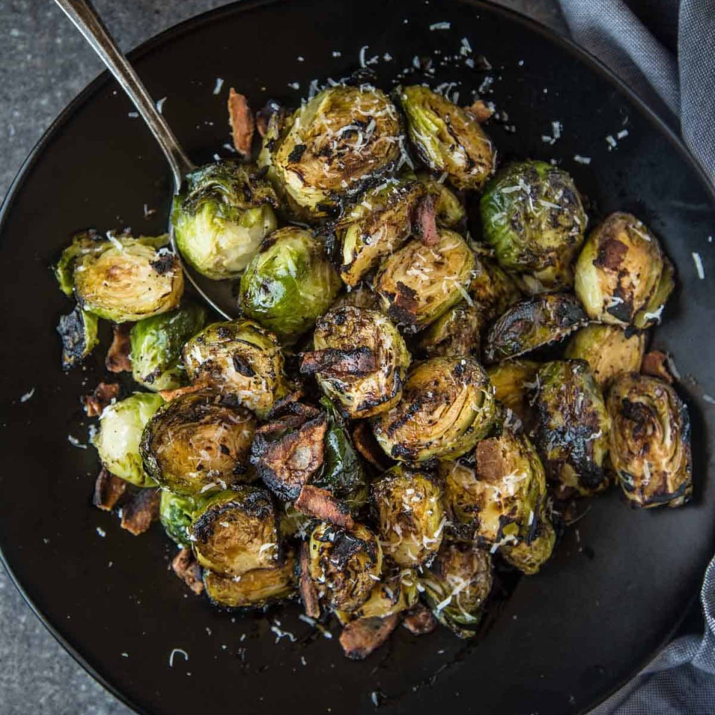 Grilled Brussels Sprouts with Balsamic and Bacon in a bowl with crispy edges.