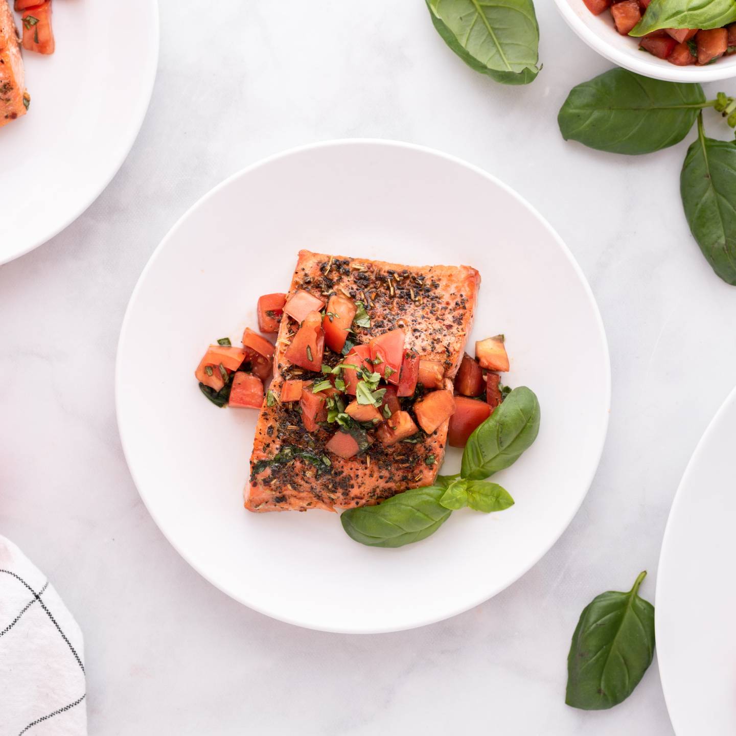 Italian salmon with a tomato basil salsa on a plate with fresh basil on the side.