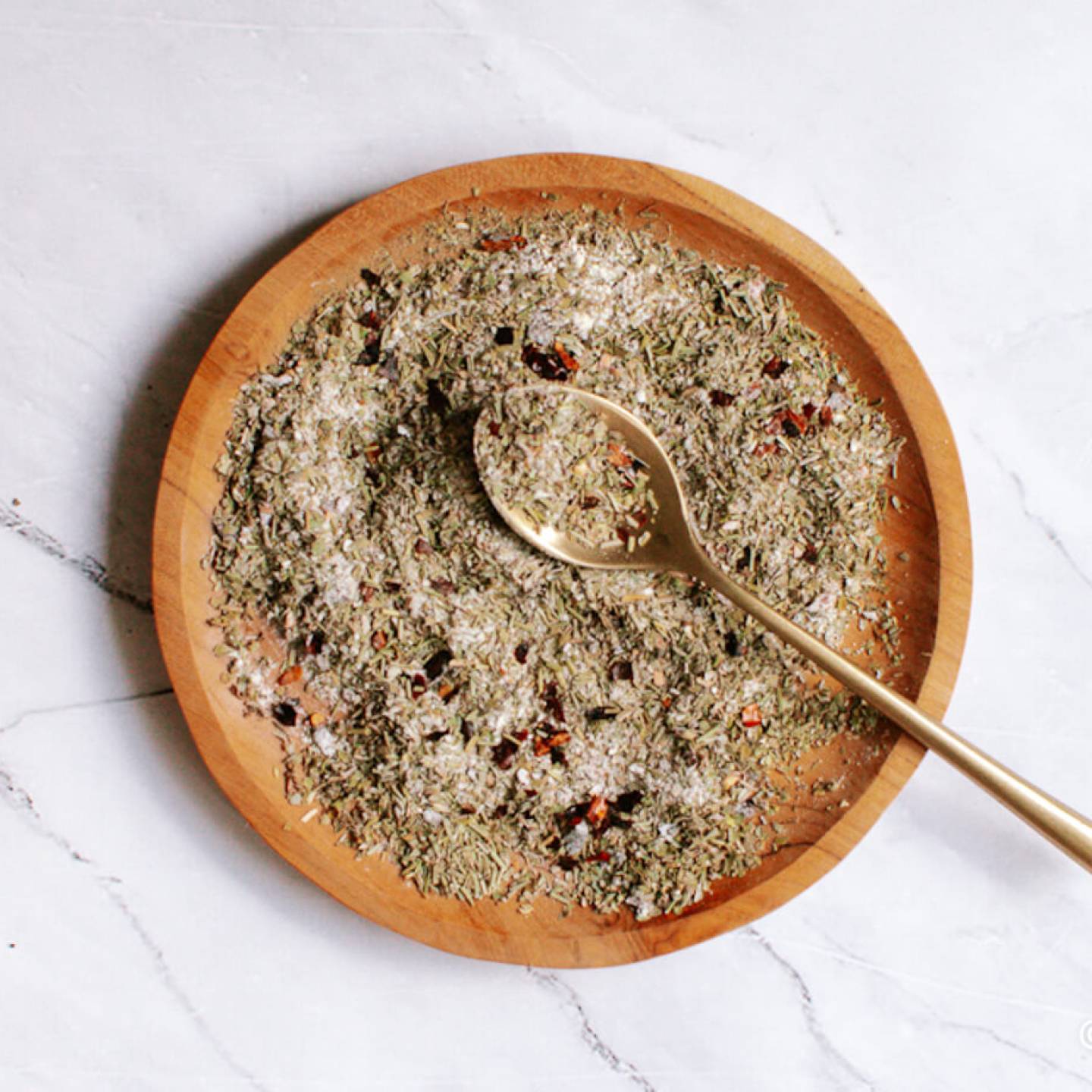 Italian seasoning mixed on a plate with oregano, basil, rosemary, thyme, garlic powder, and red pepper flakes. 