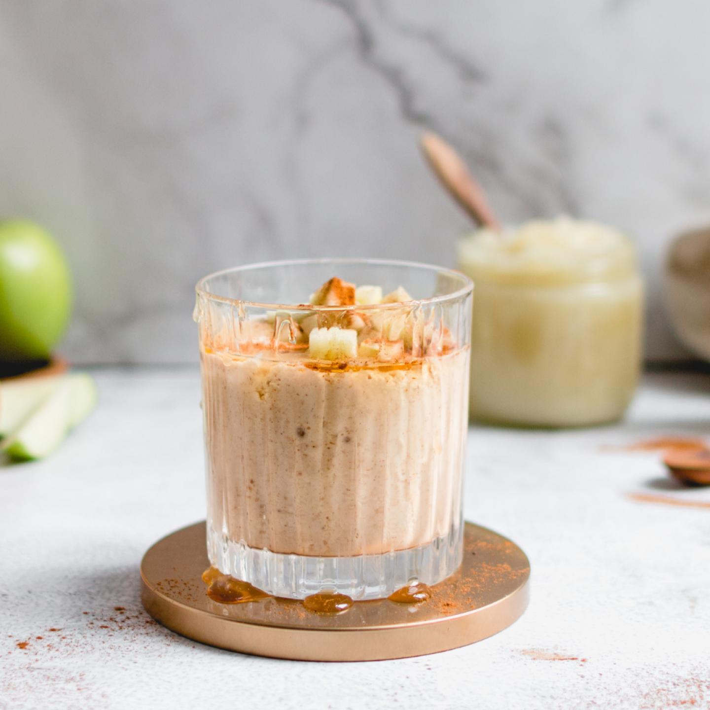 Apple banana smoothie with cinnamon, apples, bananas, and oats in a glass with apples on the side.