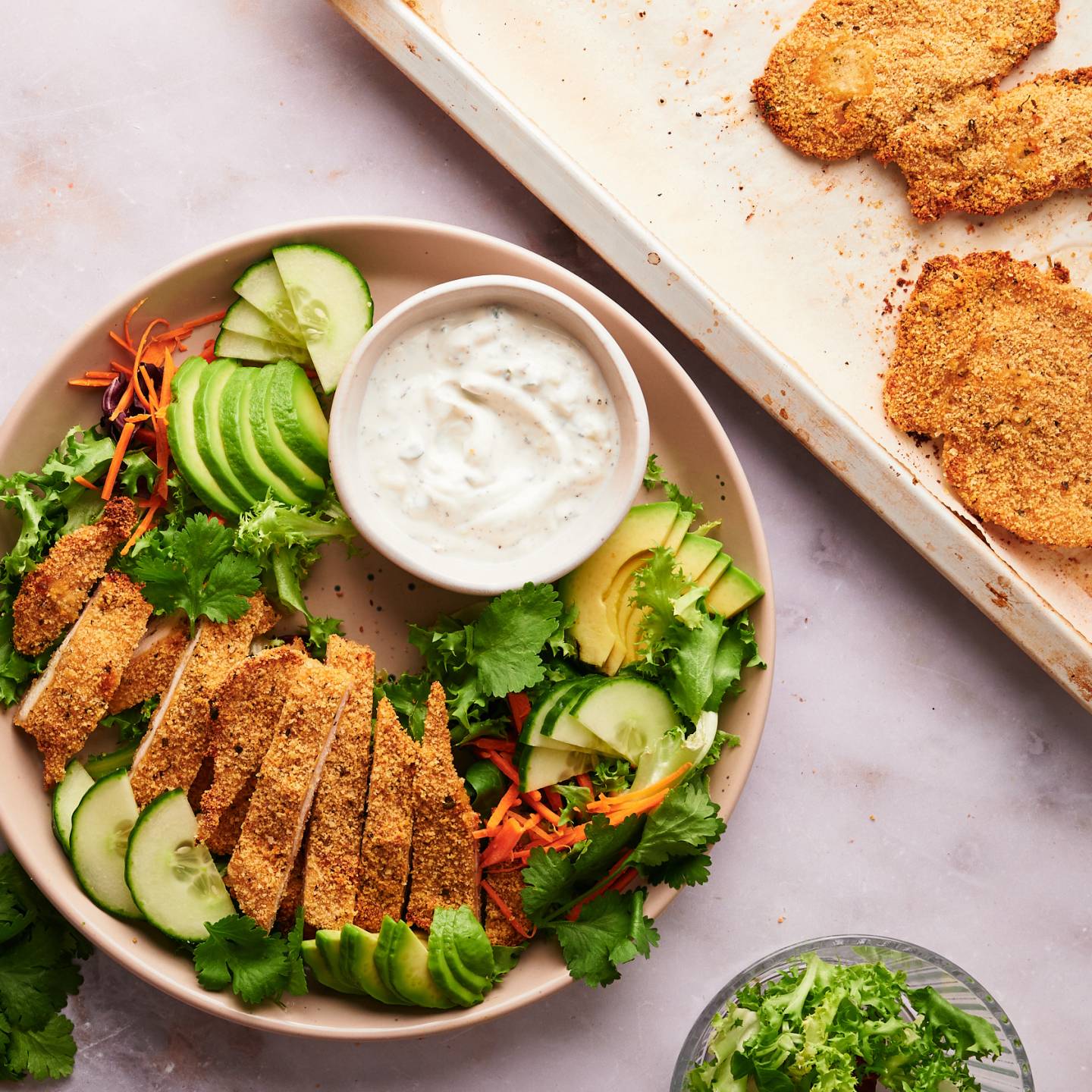 Baked chicken cutlets on a plate with salad and ranch dressing.