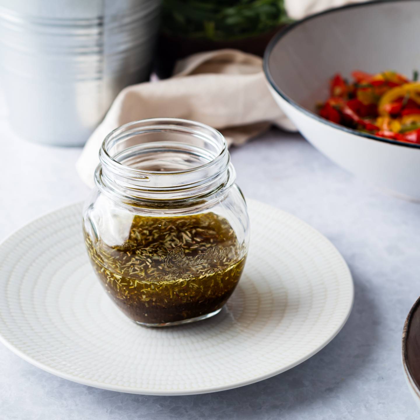 Balsamic grilled vegetable marinade in a glass jar with grilled vegetables on the side. 