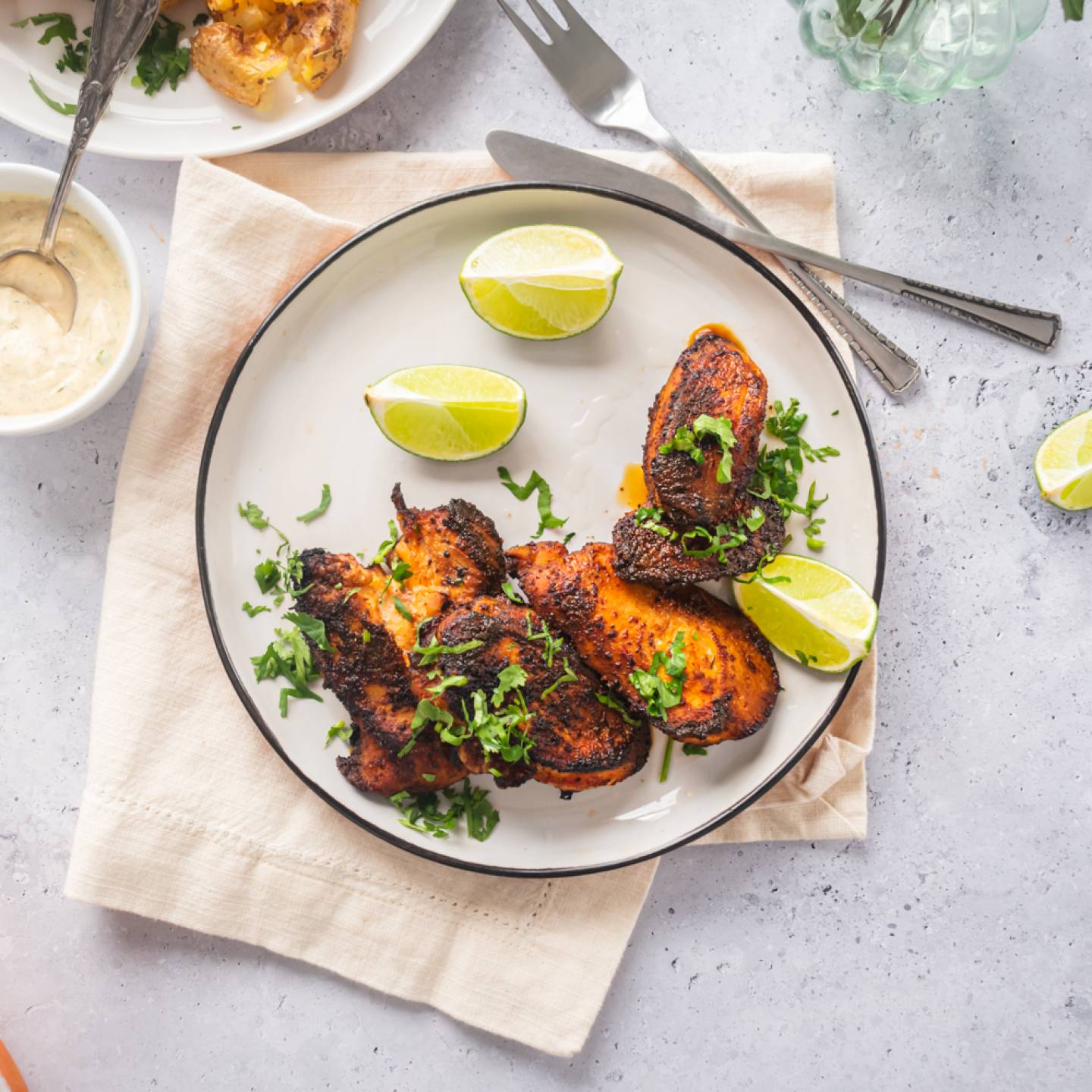 Blackened chicken breast with a crispy exterior on a plate with lime and cilantro.