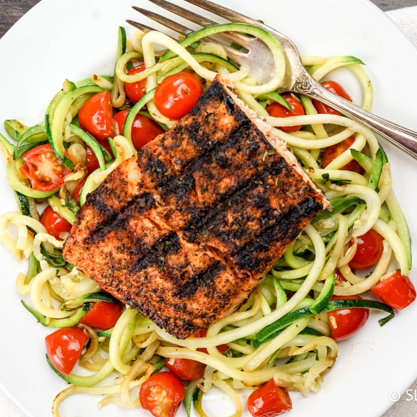 Blackened Salmon over a bed of zucchini noodles with cherry tomatoes.