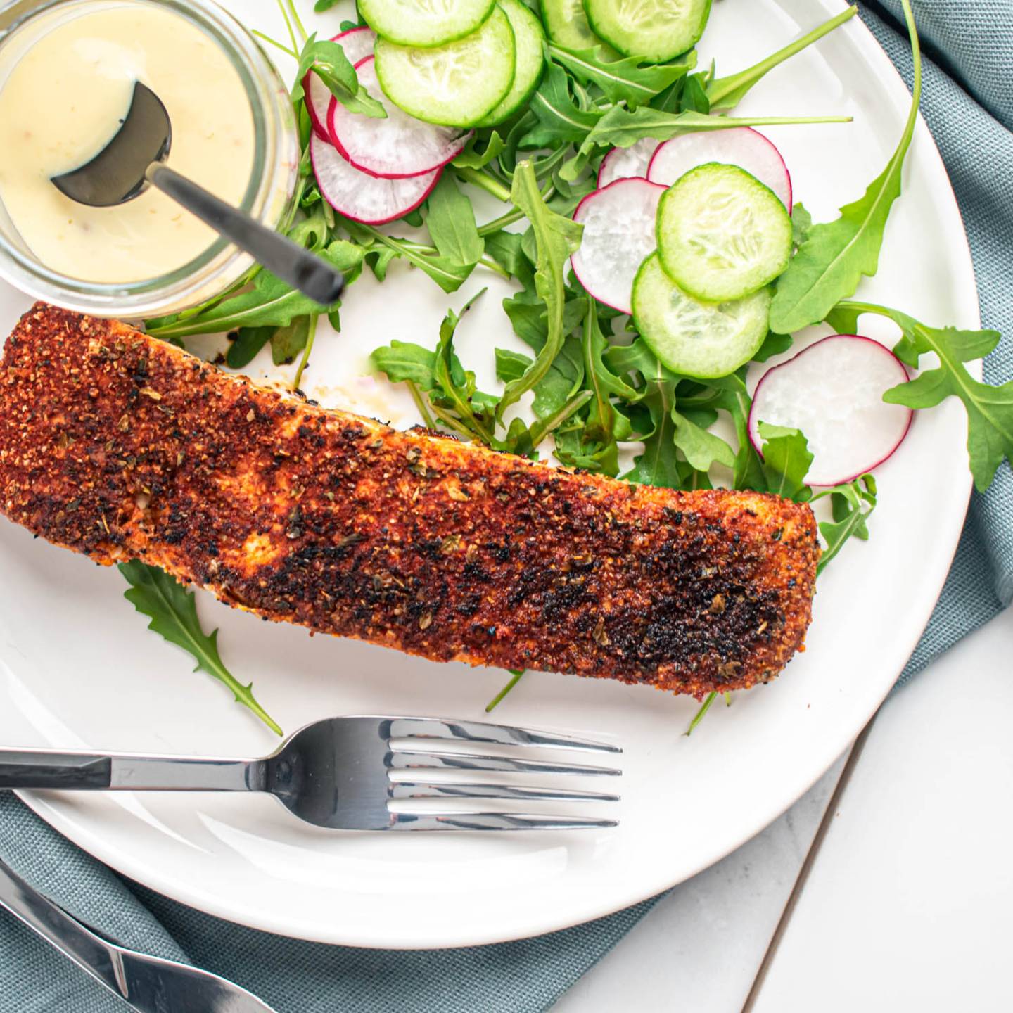 Blackened salmon with a homemade spice blend on a plate with salad.